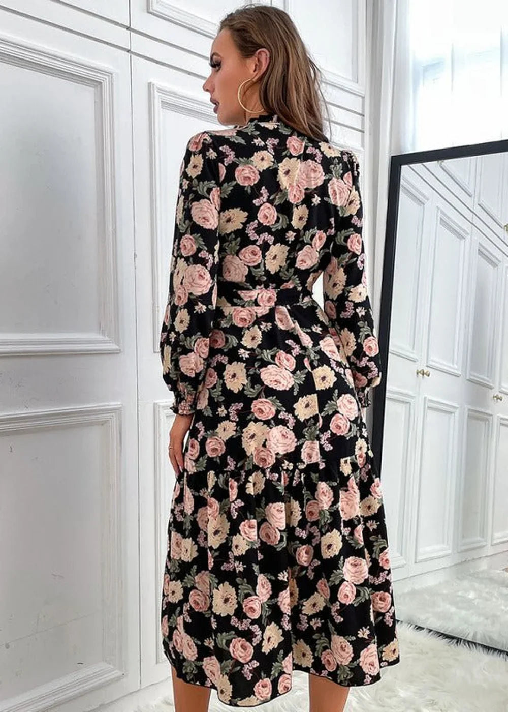 Black midi dress with a pink and cream floral pattern, long sleeves, and a tiered skirt.