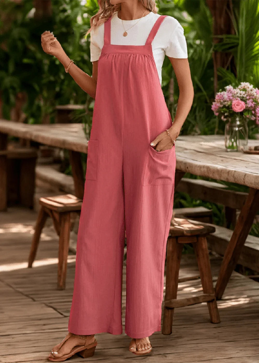 Coral wide-leg jumpsuit with square neckline and pockets, worn by a model with sandals.