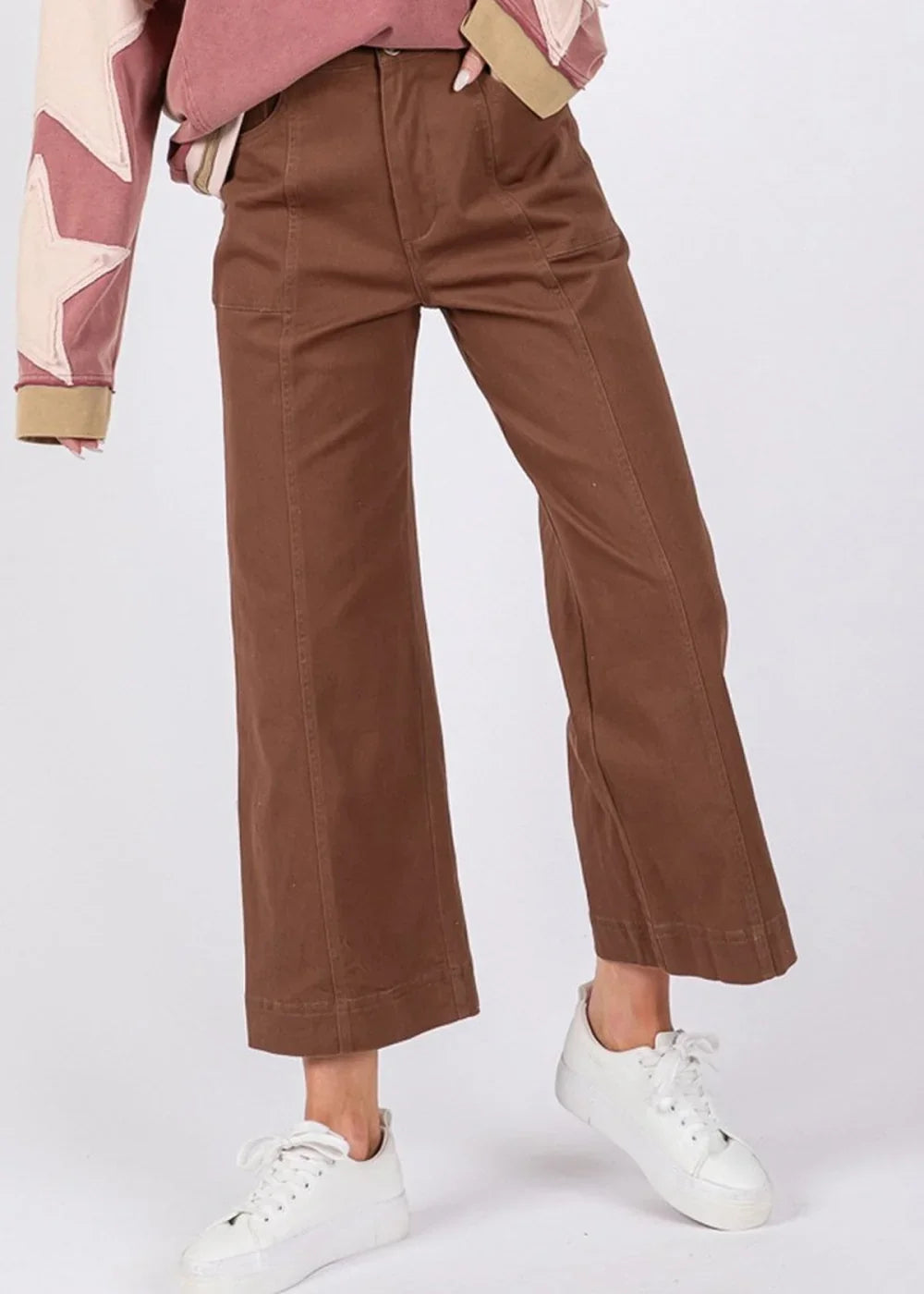 Brown wide-leg pants with visible stitching and pockets, worn with white sneakers.