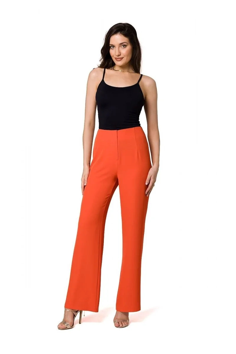 Orange wide-leg pants with a high waist on a woman wearing a black tank top and gold heels.