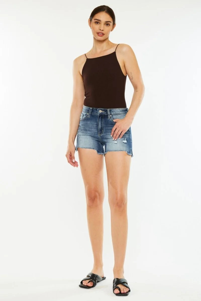 Distressed denim shorts with frayed hem and a regular fit on a model.