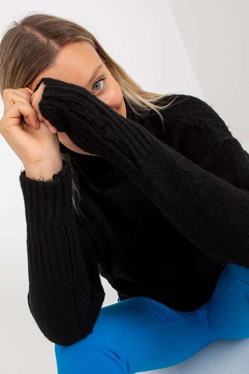 Black ribbed turtleneck sweater with frayed cuffs and bright blue leggings.