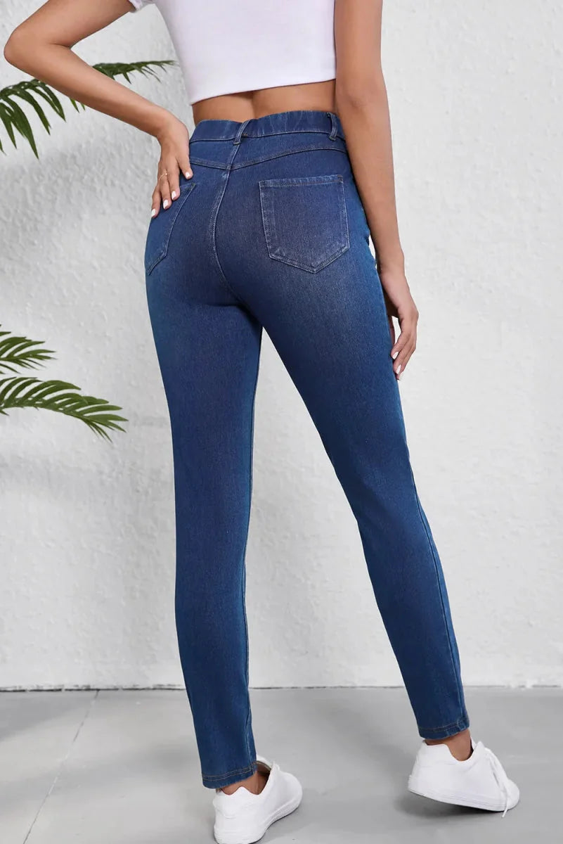 Dark wash denim jeans with a fitted silhouette and textured back pockets.