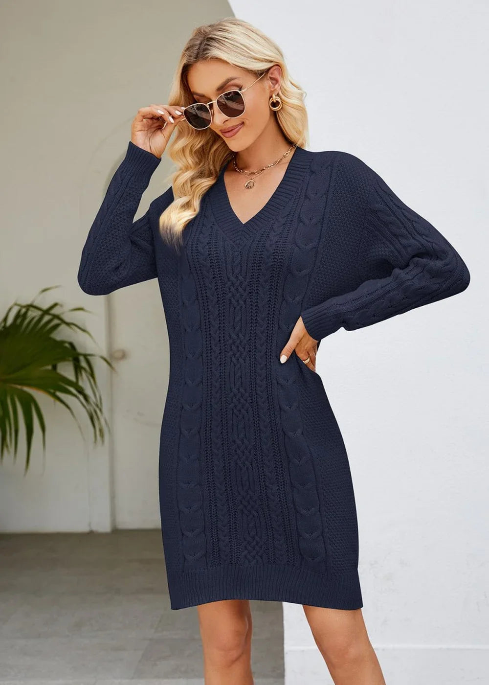 Navy blue cable knit sweater dress with V-neck and long sleeves, on a model.