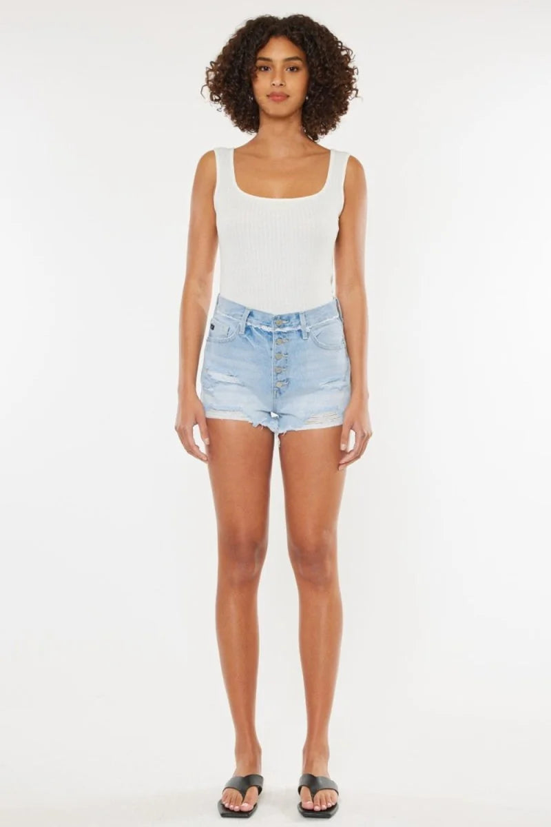 Light wash distressed denim shorts with frayed hem and button fly on a model.