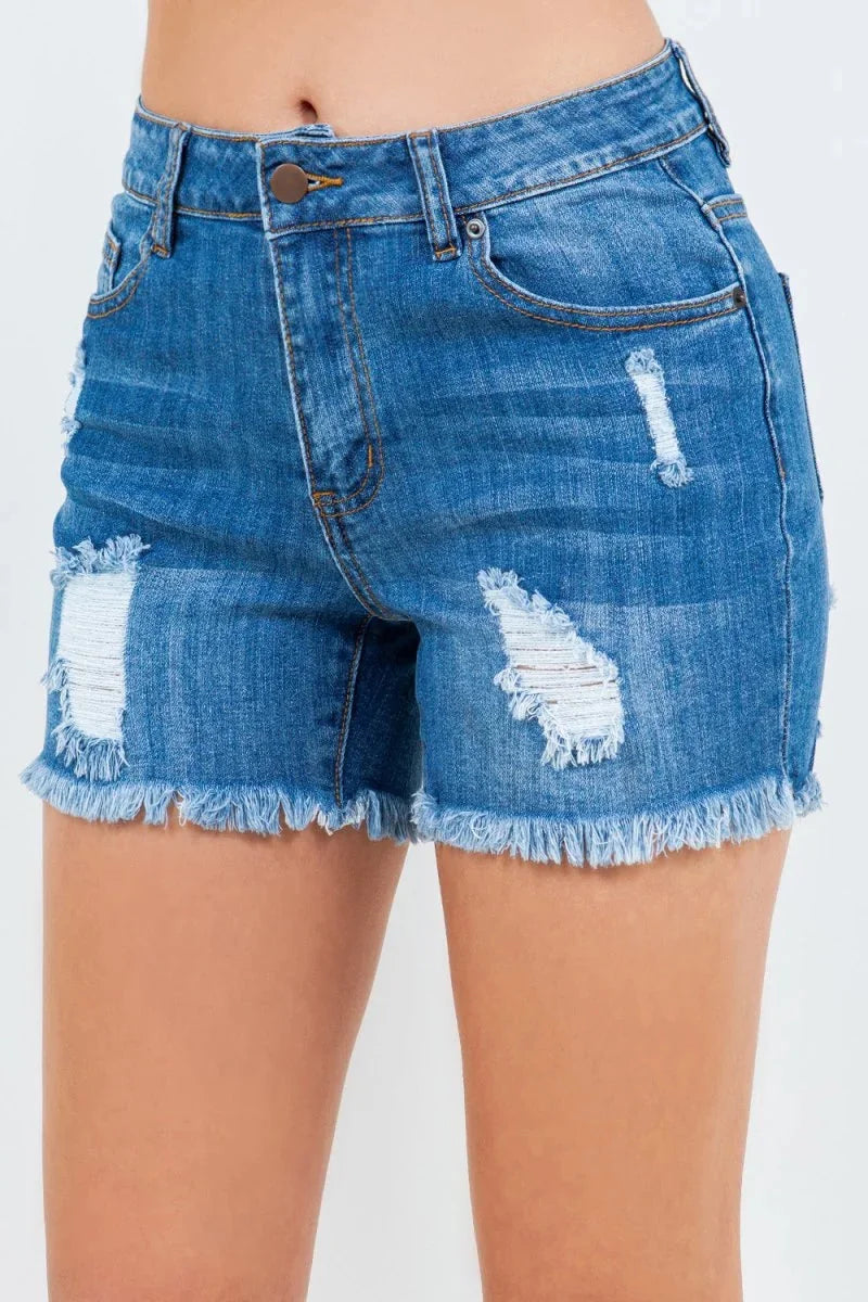 Close-up of distressed blue denim shorts with frayed hem and white thread details.