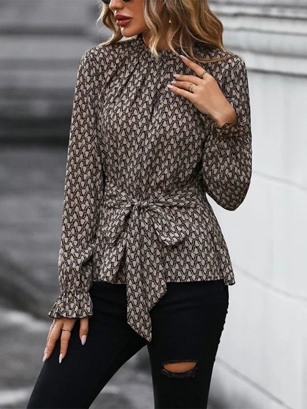 Woman in a brown and black patterned blouse with a tie waist and ruffled cuffs, paired with ripped black jeans.