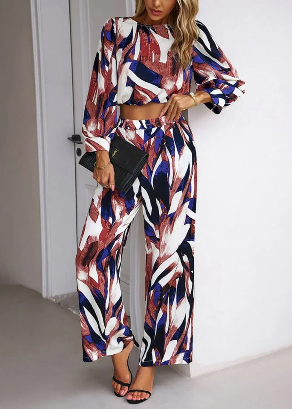 Woman in a long-sleeved crop top and wide-leg pants with a bold abstract print in red, blue, and white.