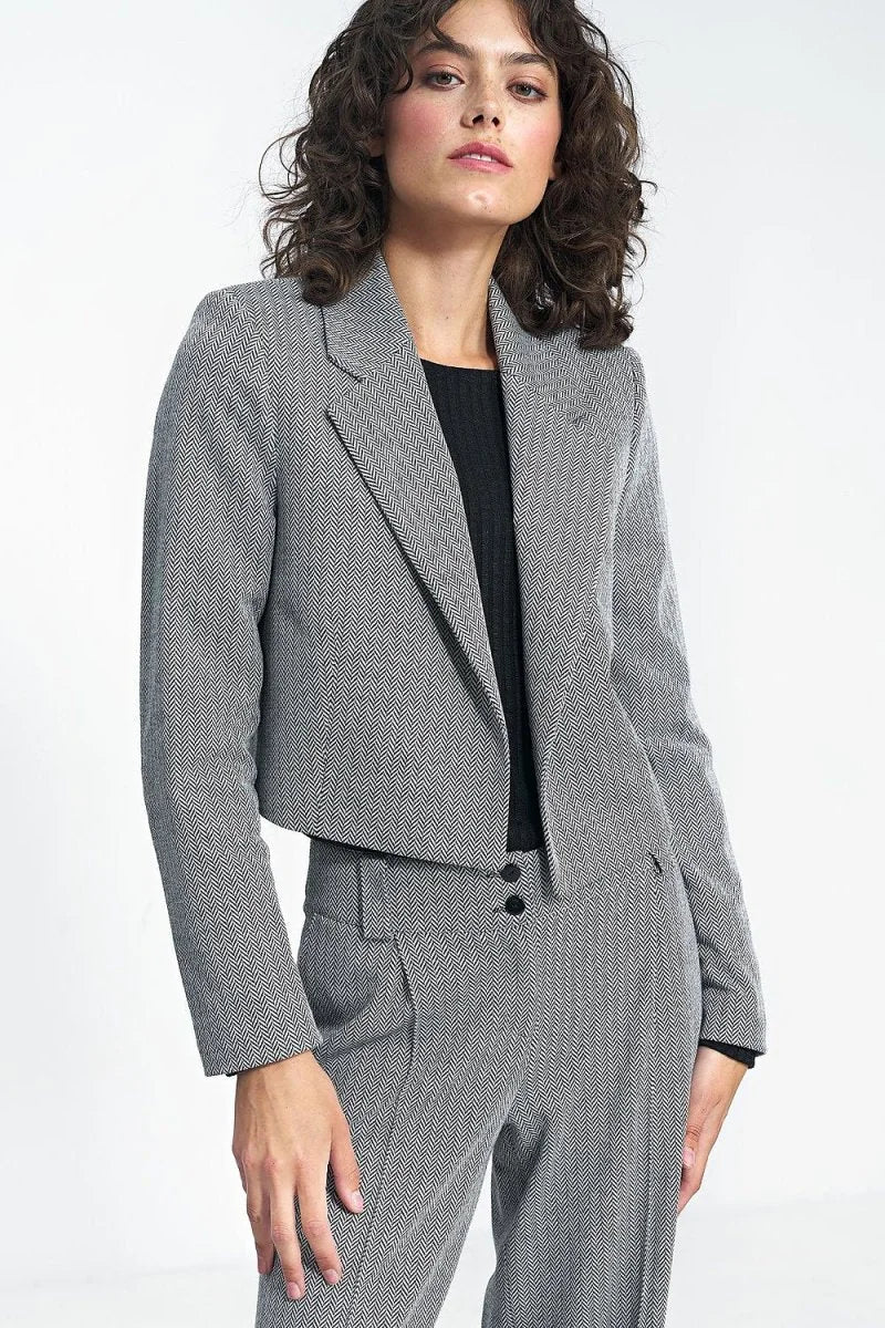 Cropped herringbone blazer with a black ribbed top and matching trousers on a model.