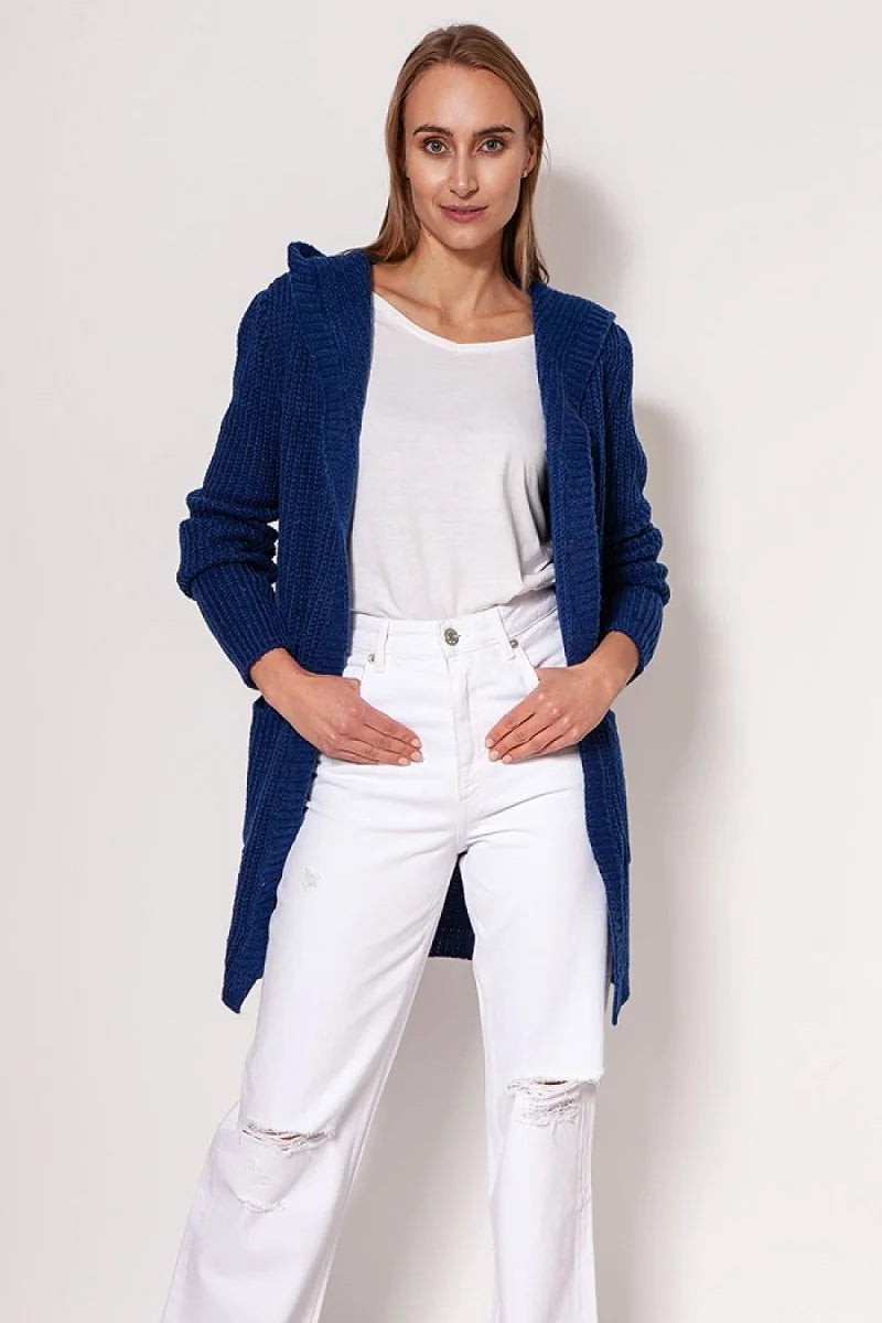 A woman models a royal blue knit cardigan with a hood and white ripped jeans.