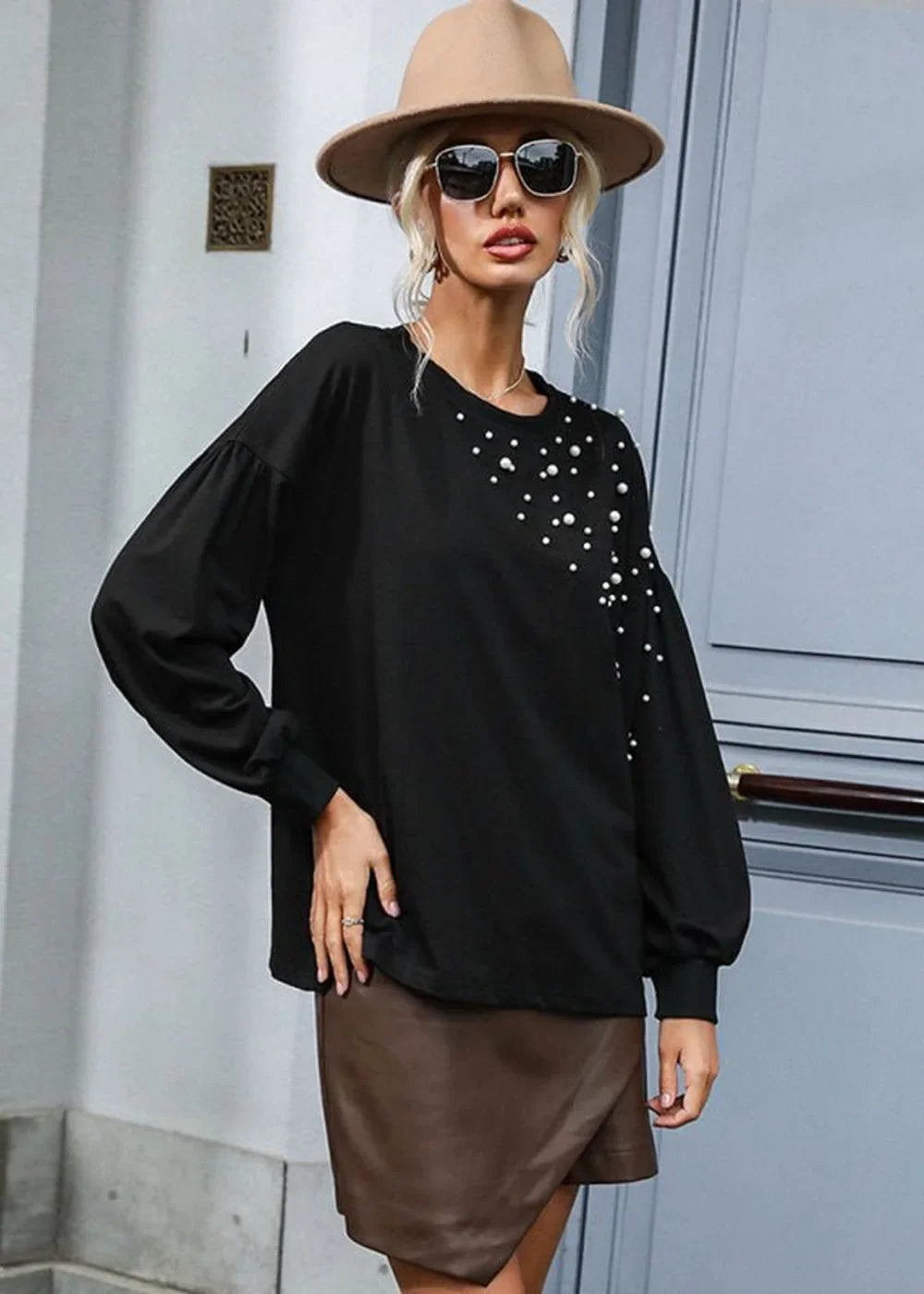Black long-sleeve top with scattered pearl embellishments on the shoulder and sleeve, paired with a brown faux leather skirt.