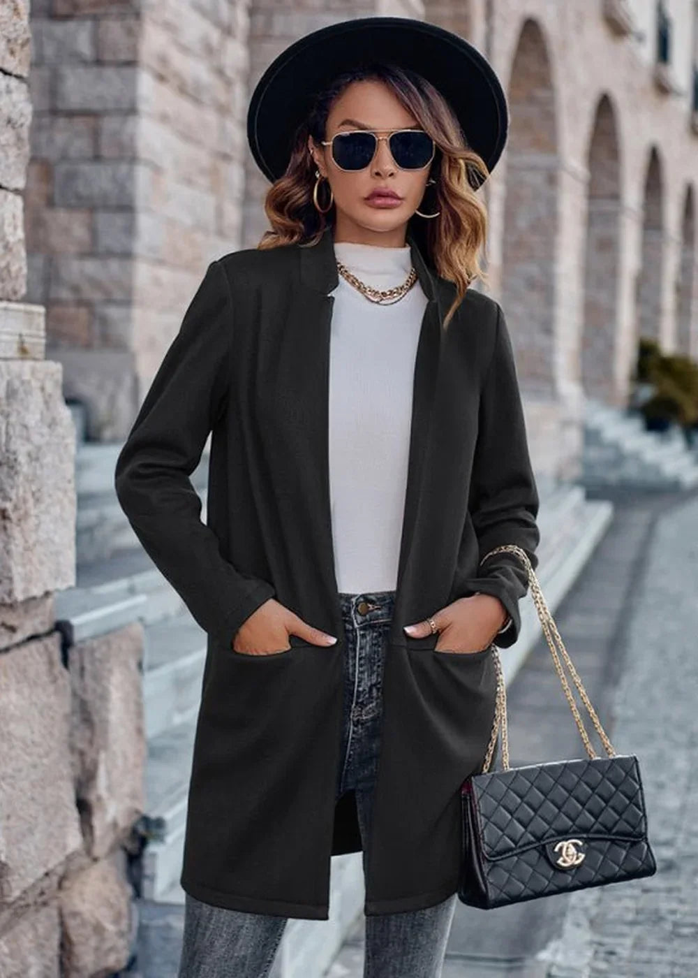 Black open-front blazer with gold chain necklace and quilted handbag on model.