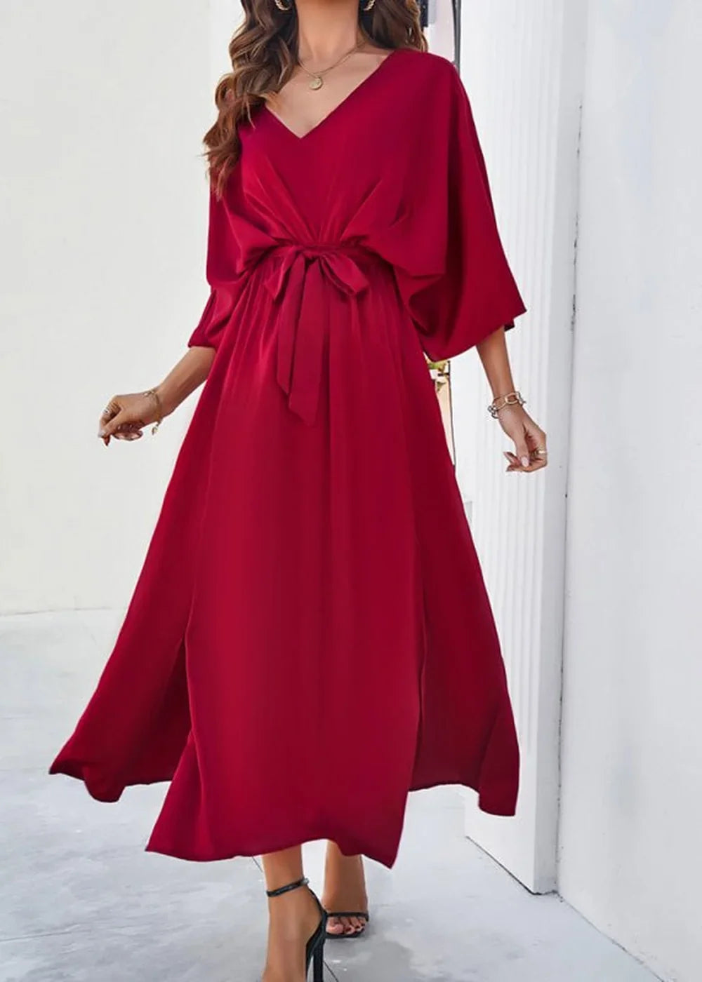 Red V-neck flowy dress with a tie waist and thigh-high slits, worn by a model.