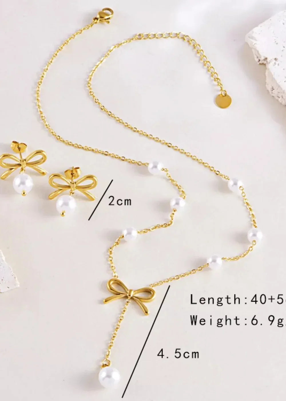 Gold-toned necklace with pearl accents and a bow charm, paired with matching bow earrings.