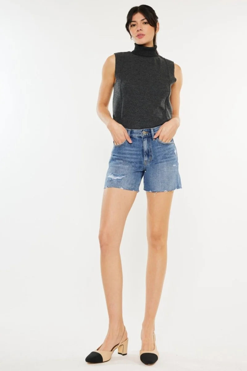 Distressed denim shorts with frayed hem and a regular fit on a model.