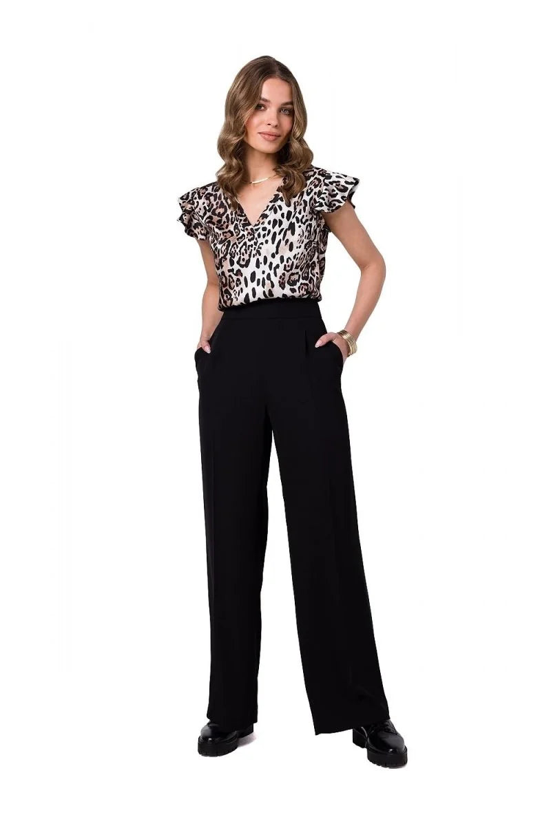 Woman in black wide-leg pants with pockets and a leopard print top with ruffled sleeves.