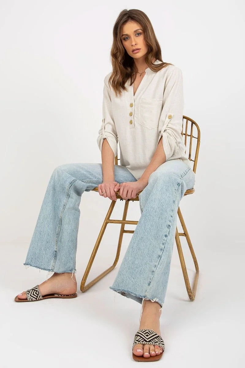 Woman in light beige linen-blend shirt with rolled sleeves, light blue wide-leg jeans with frayed hem, and black and white...
