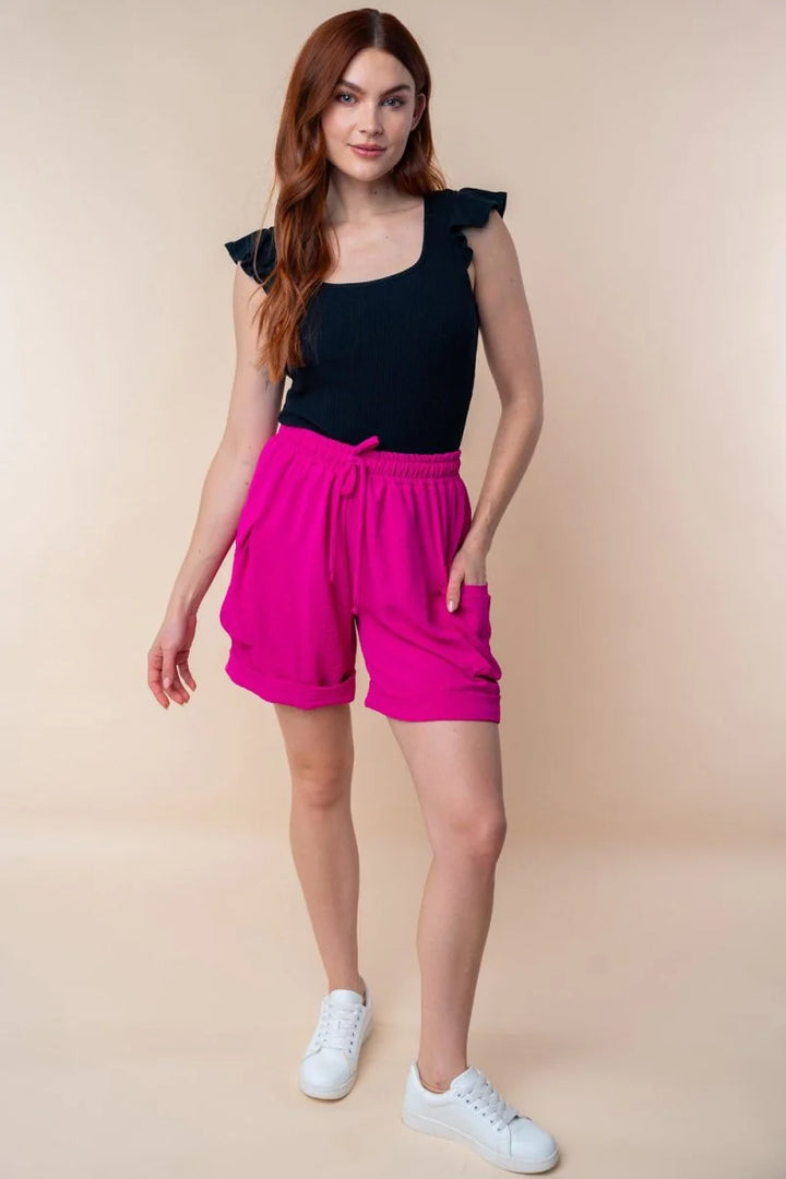 Fuchsia shorts with drawstring waist and cuffed hems, on model