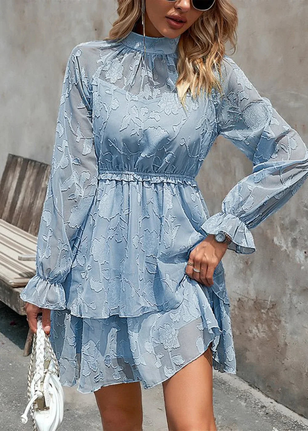 Light blue floral embroidered dress with ruffled high neck and tiered skirt.