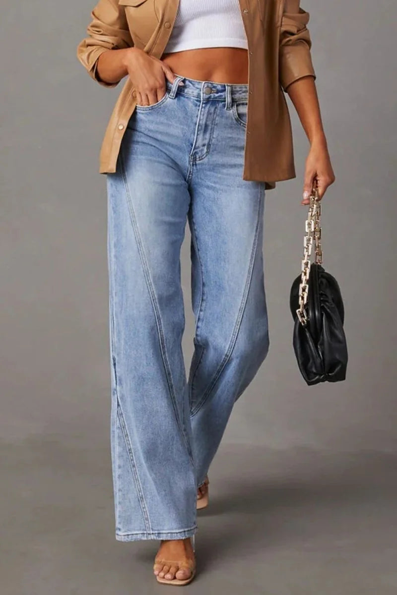 Light wash wide-leg jeans with contoured stitching and a tan jacket with a white crop top.