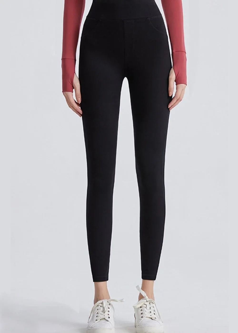 Black high-waisted leggings with a smooth texture and white sneakers on model.