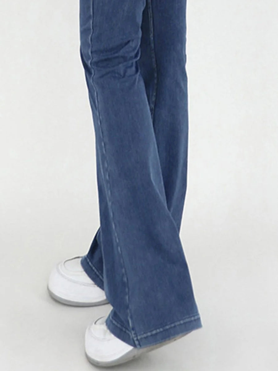 Blue denim flared pants with white sneakers, showing a close-up of the legs and feet.