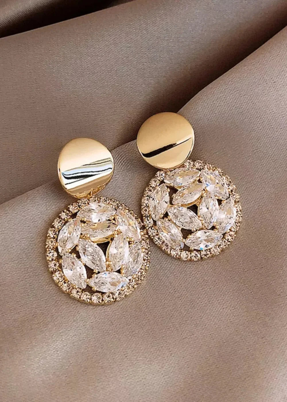 Gold-plated earrings with round studs and circular pendants adorned with clear, marquis-cut rhinestones.