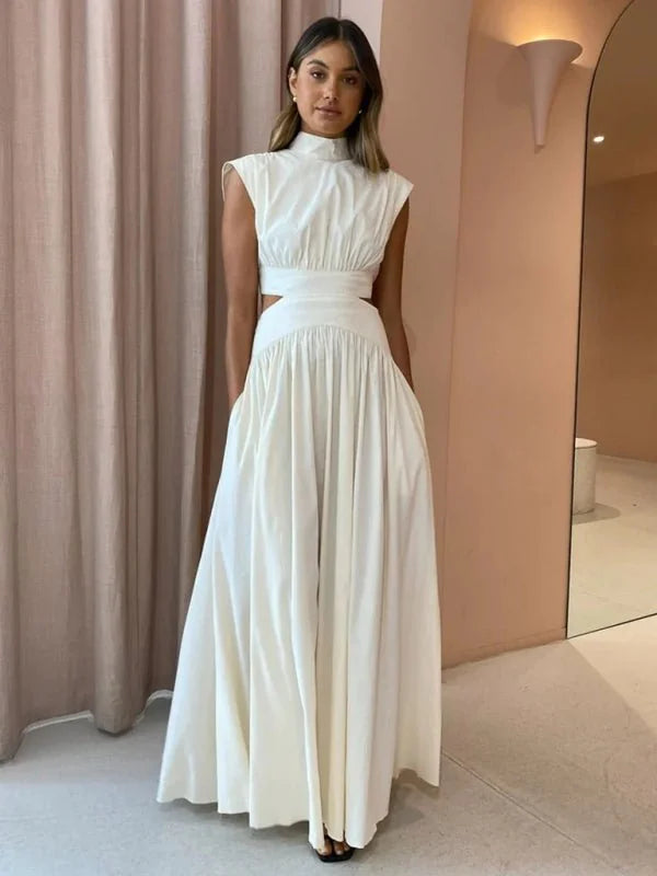 White sleeveless maxi dress with cutouts at the waist and a high neckline, on a model.