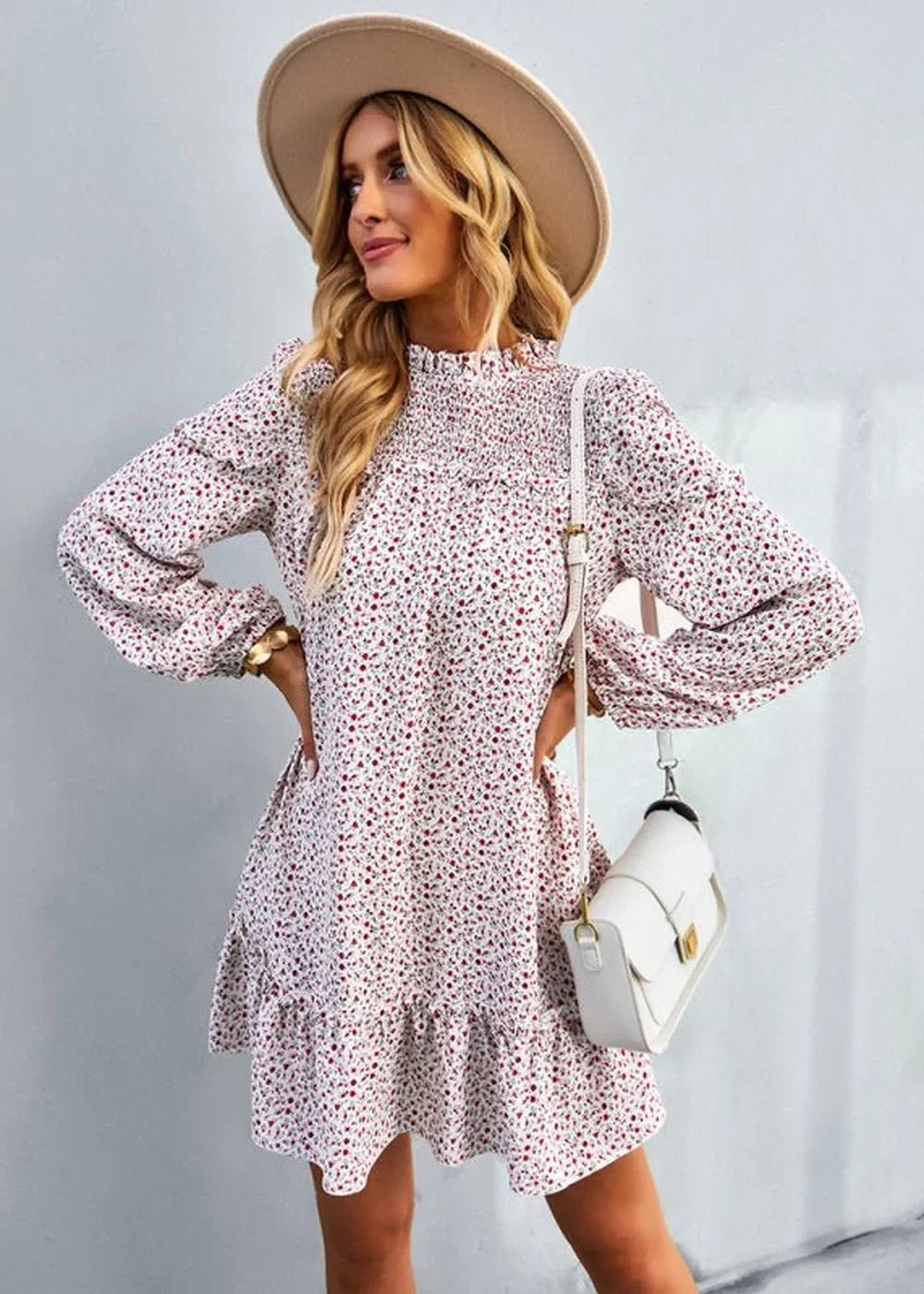 Woman in a white floral print dress with ruffled hem, long sleeves, and a wide-brim hat.