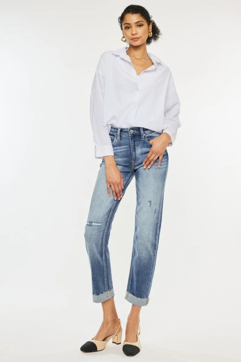 Woman in cuffed, distressed medium-wash jeans with a white button-down shirt and beige and black slingback heels.