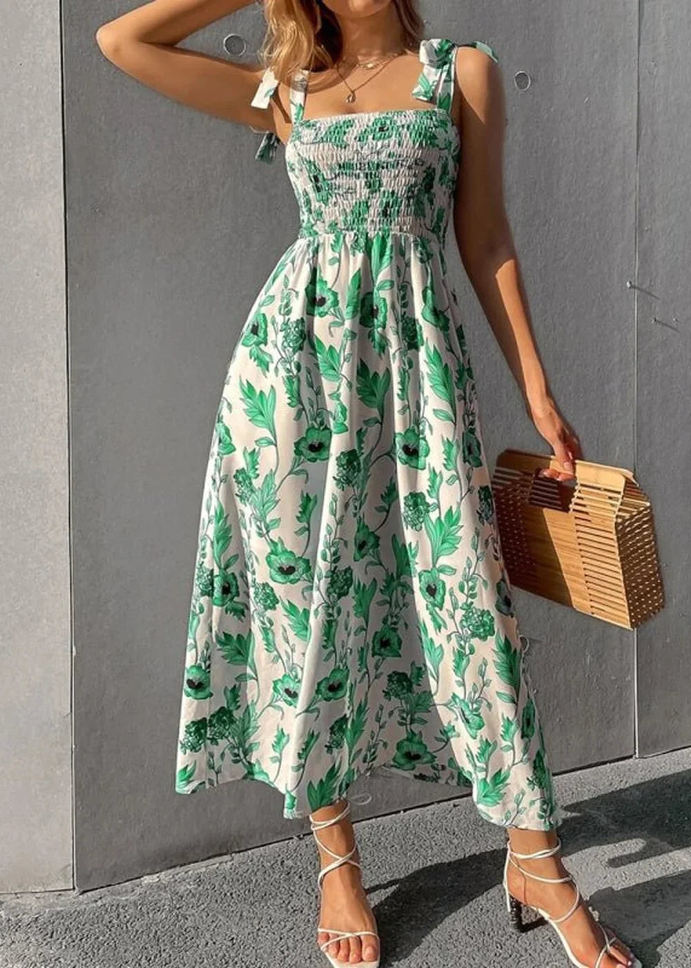 Woman in white floral midi dress with green leaves and flowers, tie straps, and white strappy heels.
