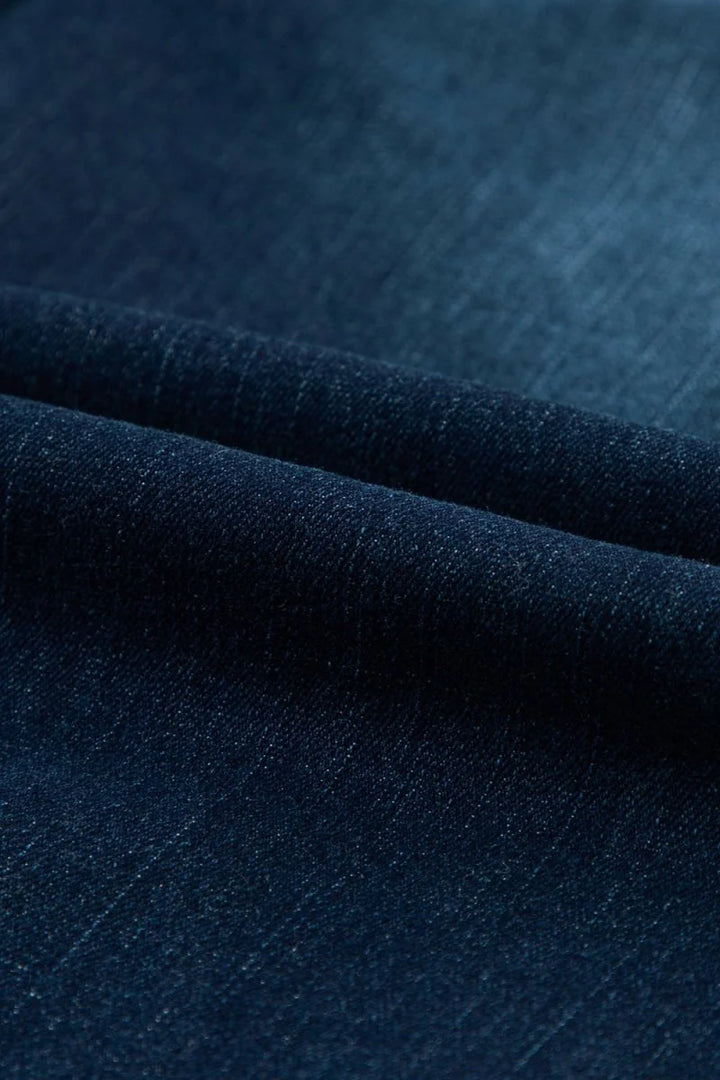 Close-up of dark blue denim fabric with a textured weave.