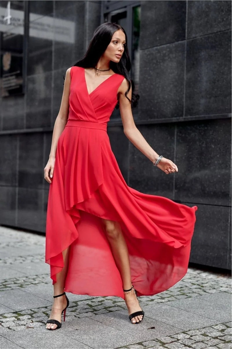 Woman in a flowing red asymmetrical dress with a V-neck and strappy black heels.