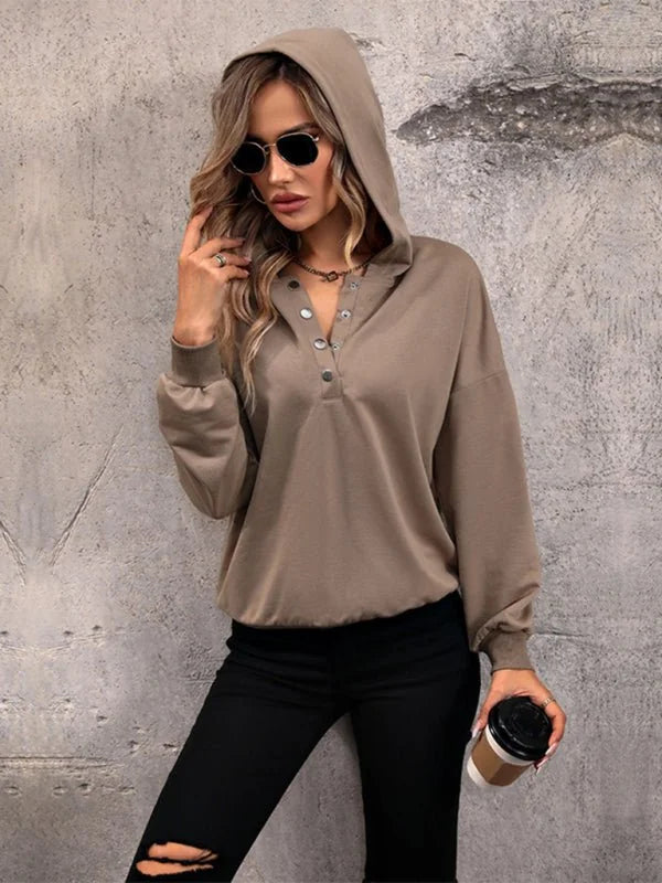 Taupe hooded sweatshirt with snap button neckline and black distressed jeans.