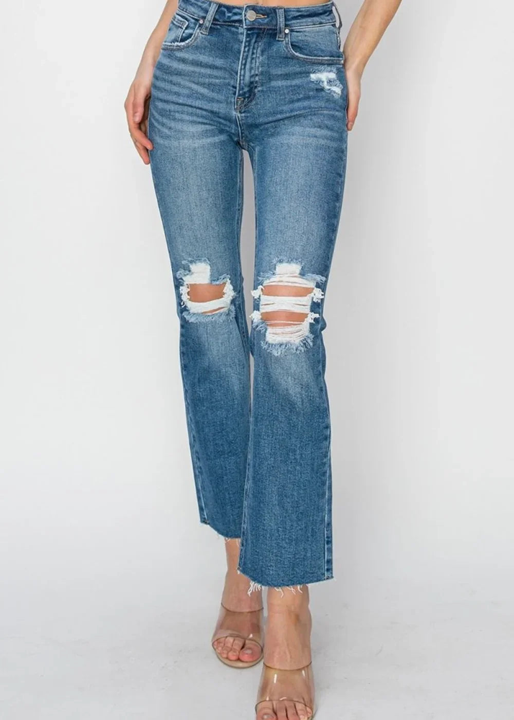 Distressed medium wash denim jeans with a straight leg and frayed hem, shown on model.