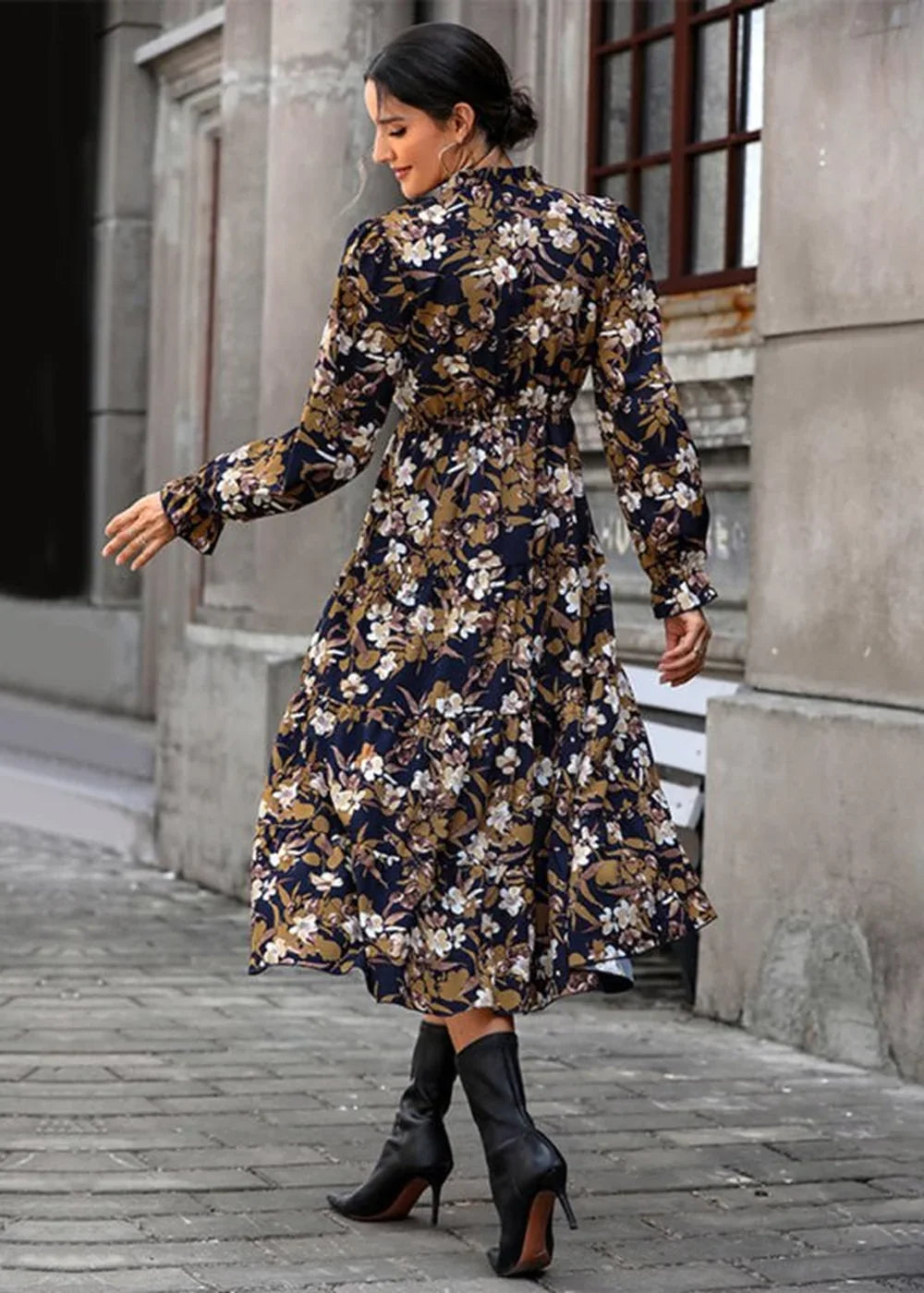 Navy blue dress with a floral print of white and golden brown flowers, featuring long sleeves and a midi skirt.