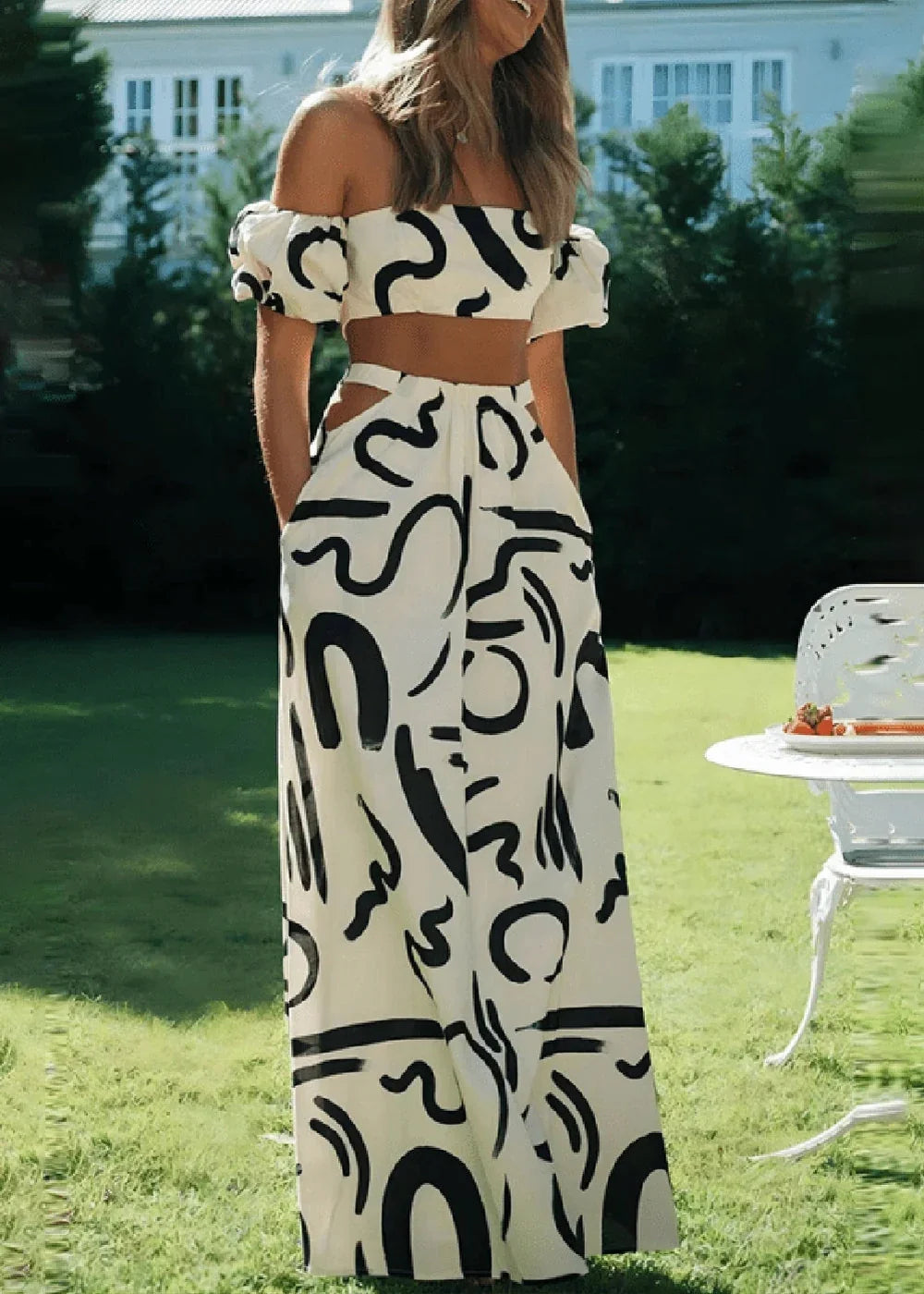 White and black abstract print off-the-shoulder crop top and wide-leg pants set on model.