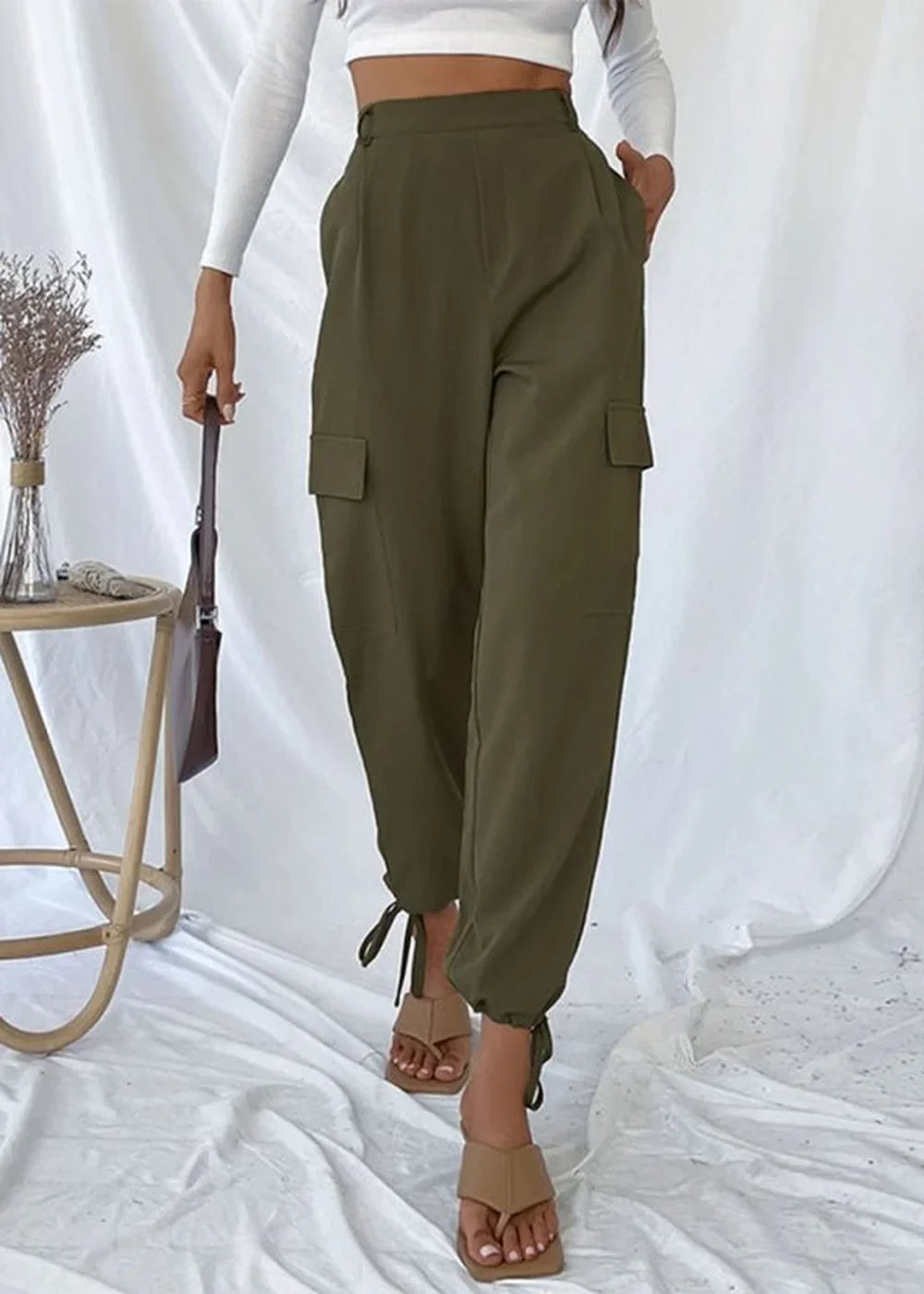 Olive green cargo pants with tie ankles and front pleats, on model.