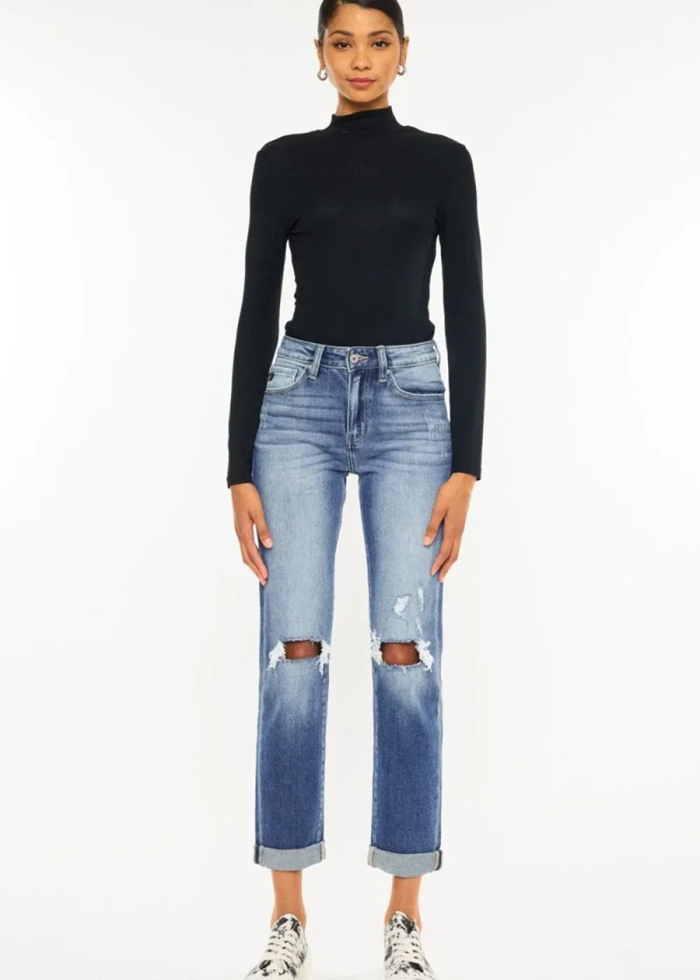 Distressed denim jeans with ripped knees and cuffed hems, worn by a model.