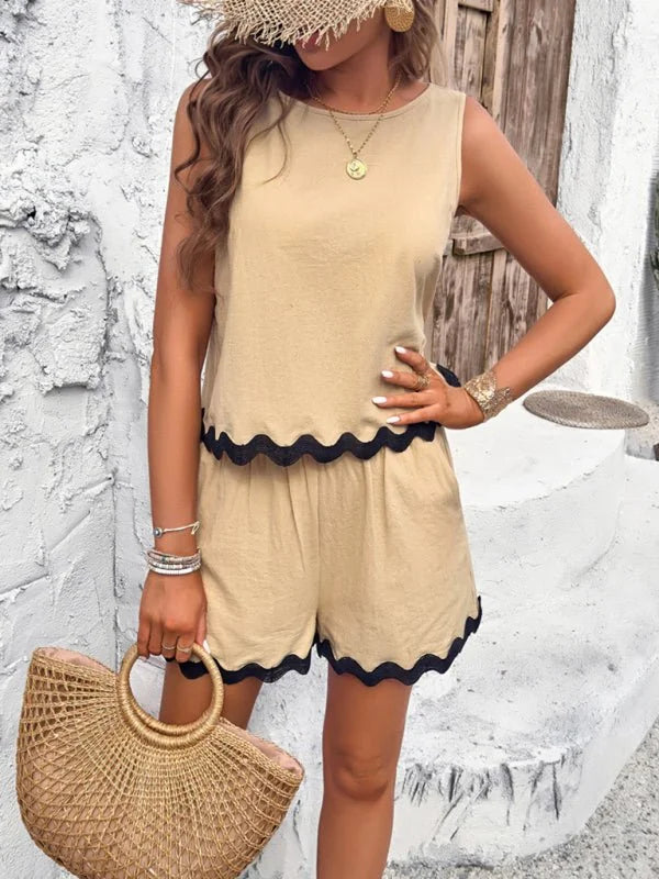 Woman in tan scalloped top and shorts with black trim, holding a straw bag.