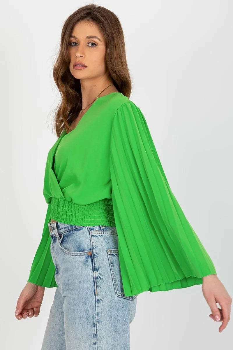 Bright green blouse with pleated bell sleeves and smocked waist, paired with light wash jeans.