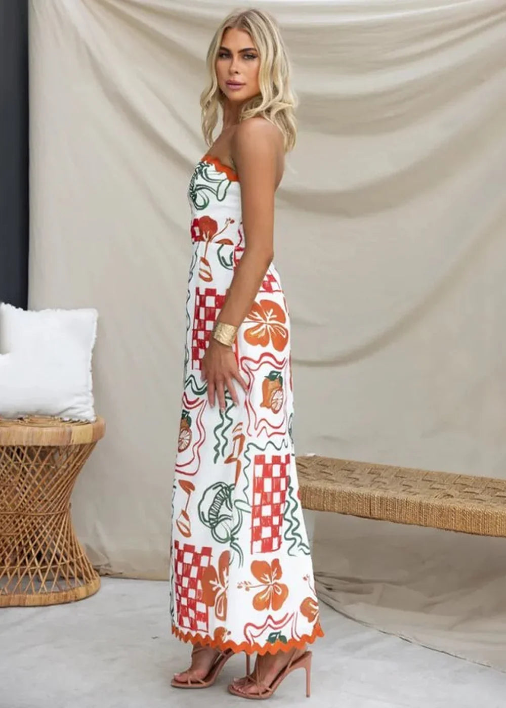 Strapless maxi dress with colorful fruit and checkerboard print, scalloped hem, on model.