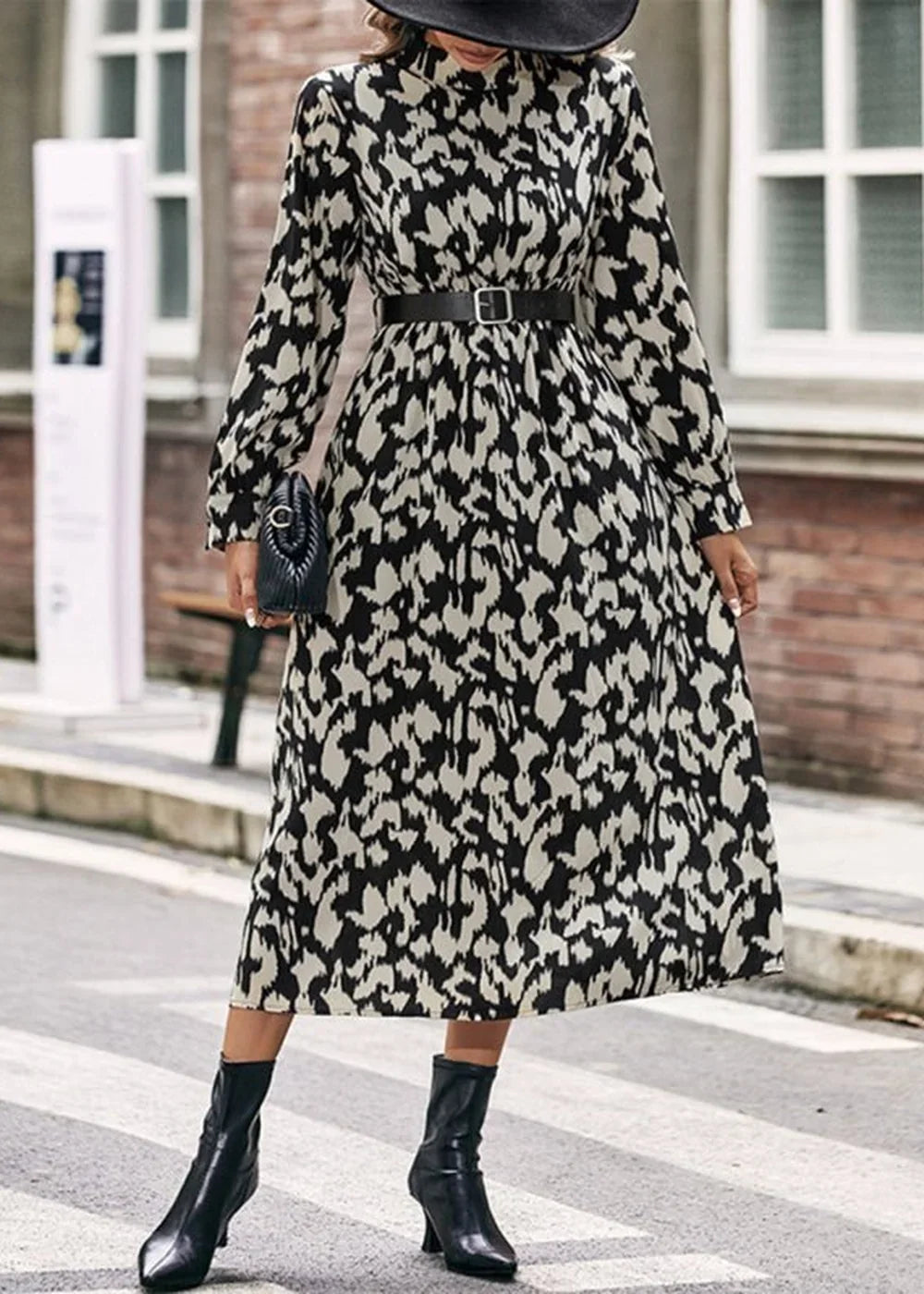 Black and cream abstract print midi dress with long sleeves, black belt, and black ankle boots.