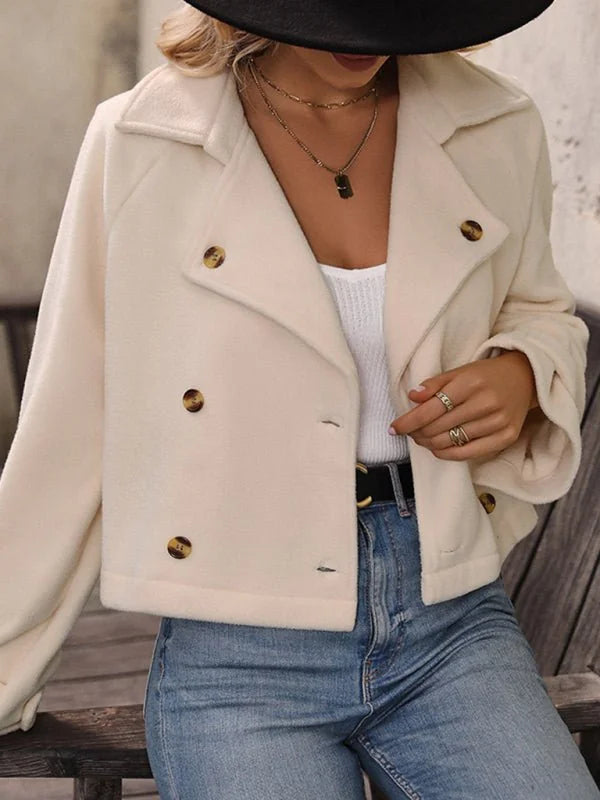 Creamy white double-breasted jacket with gold buttons, textured fabric, and blue jeans.
