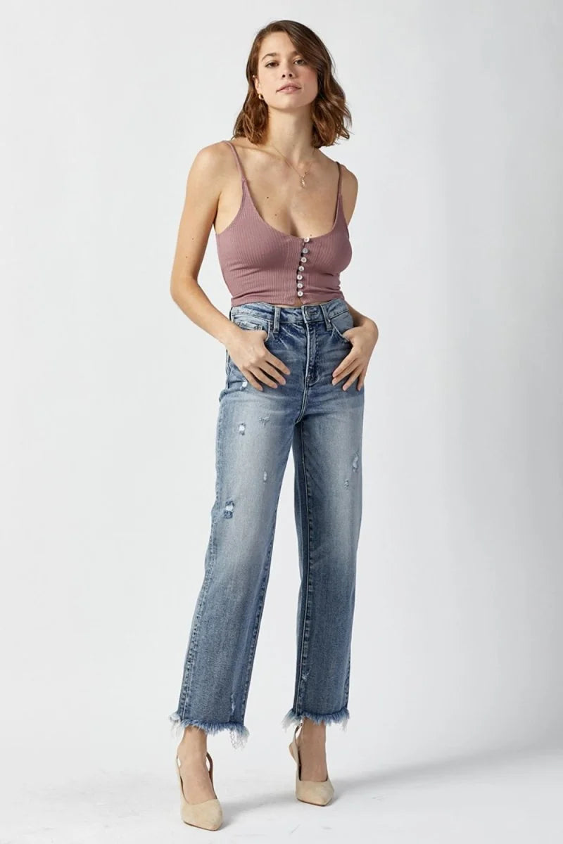Light wash, distressed denim jeans with a frayed hem on a model.
