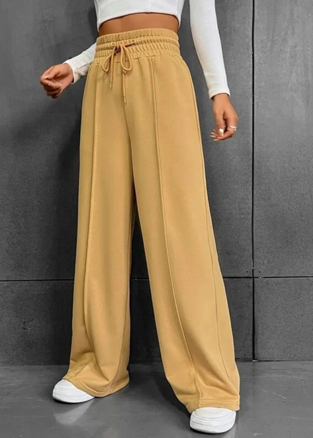 Camel wide-leg sweatpants with drawstring waist and stitched seams, worn with white sneakers.