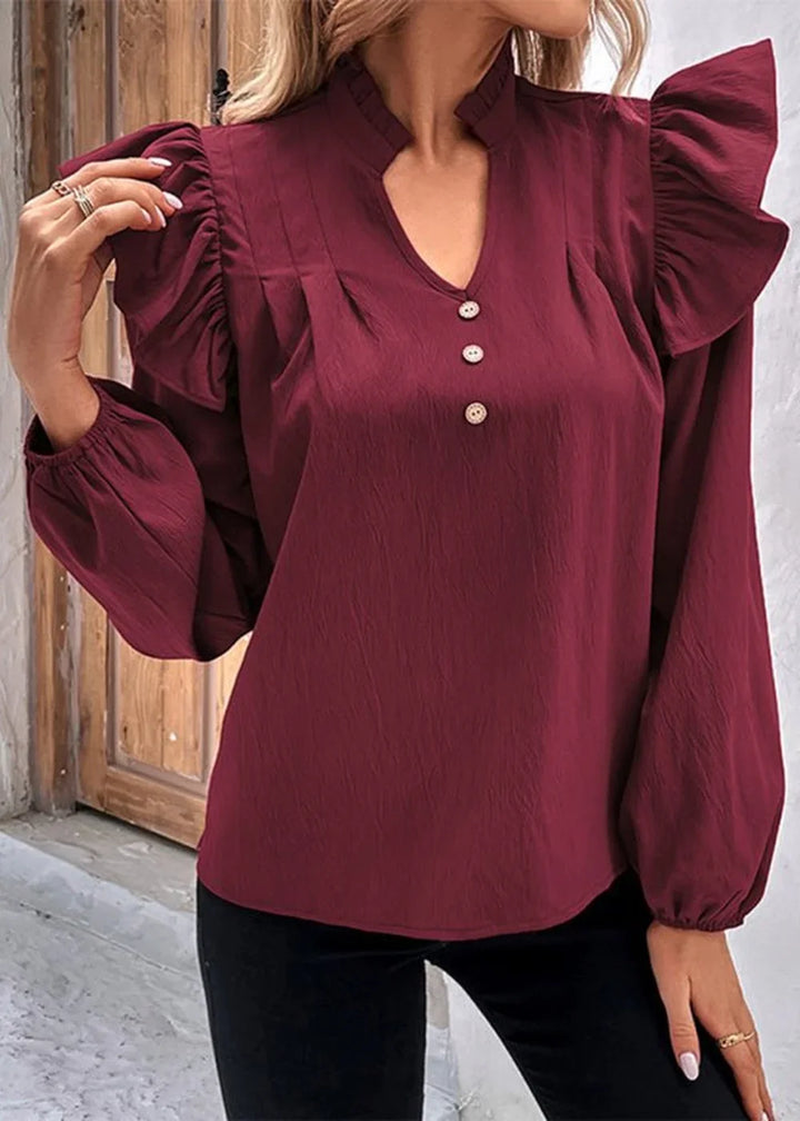 Maroon blouse with ruffled sleeves, v-neck, and button details in a textured fabric.