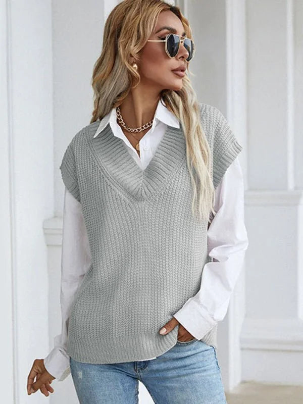 Light grey knitted v-neck sweater vest layered over a white collared shirt, worn by a model with blonde hair and sunglasses.