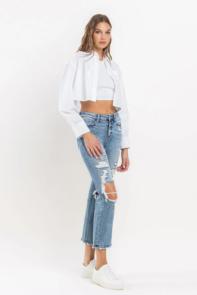 Distressed light wash denim jeans with ripped knees and frayed hem on model.
