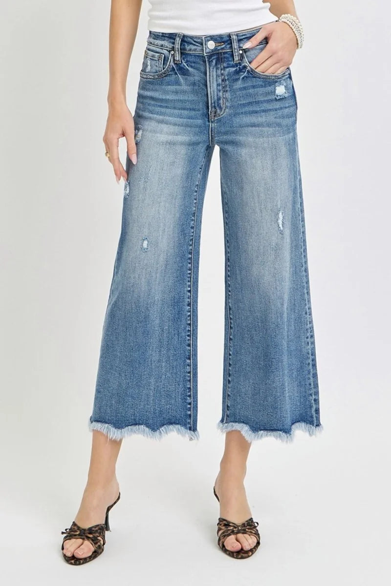 Distressed denim wide-leg cropped jeans with frayed hem, on model.